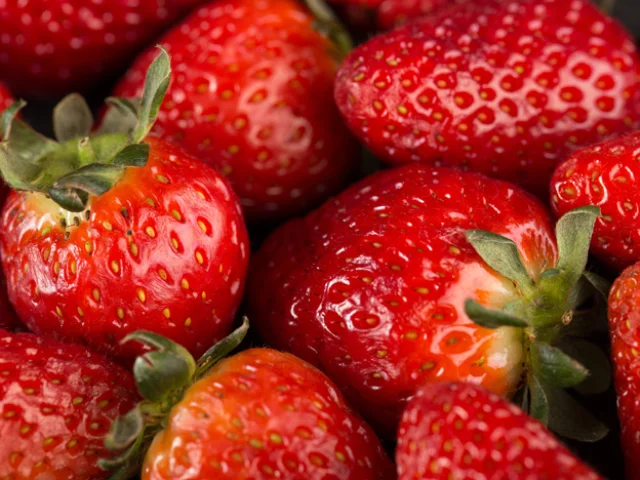 yummy strawberries red mellow ripe with green leafs on dark desk